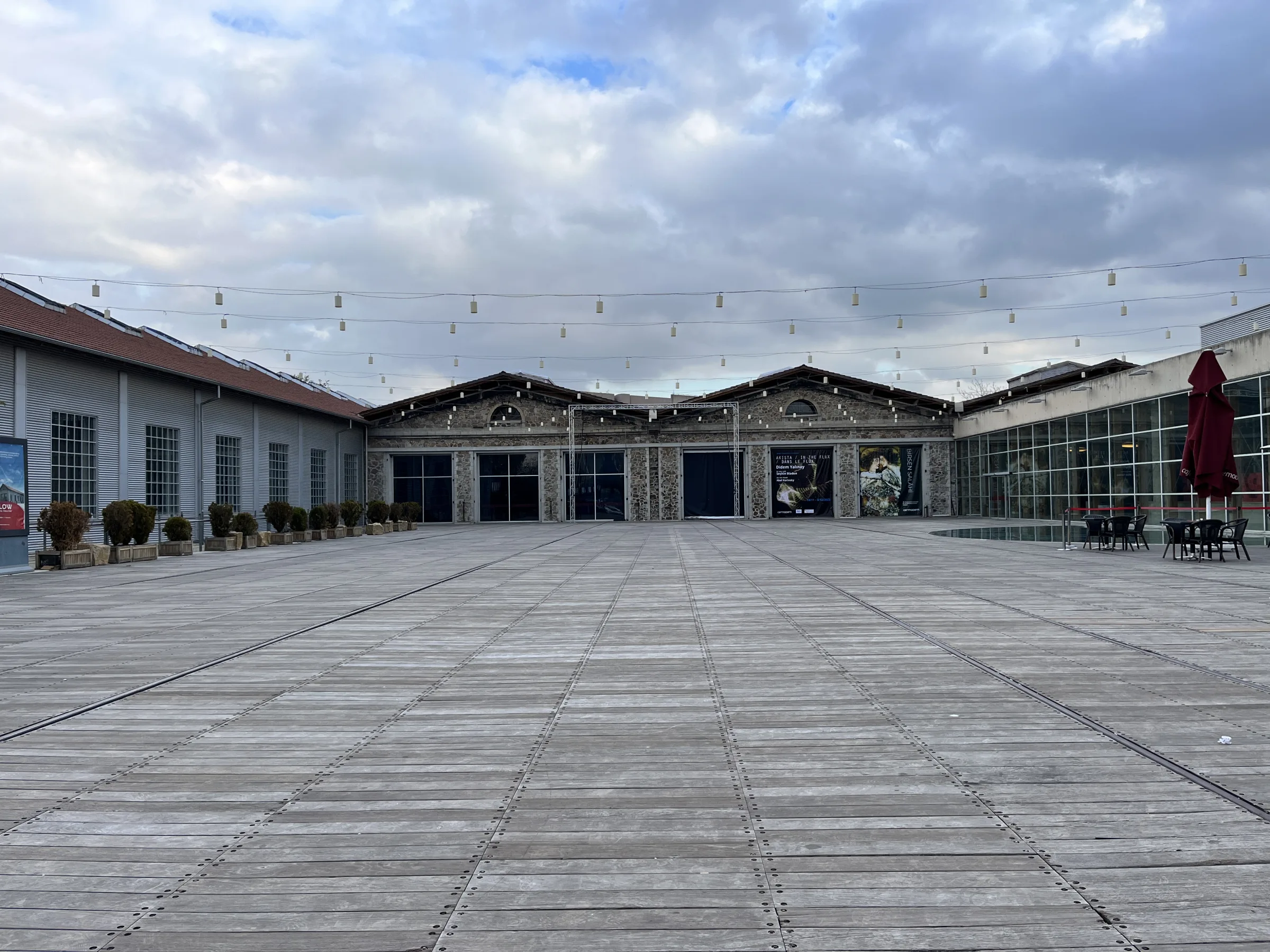 CerModern courtyard with former railway workshop façades and tracks set into the wooden deck