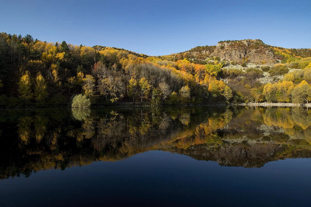 Autumn trees and a rocky hillside reflected in the water of Karagöl in Çubuk