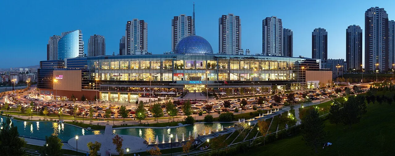 Panora shopping centre illuminated at dusk, with its glass dome, front gardens and surrounding towers