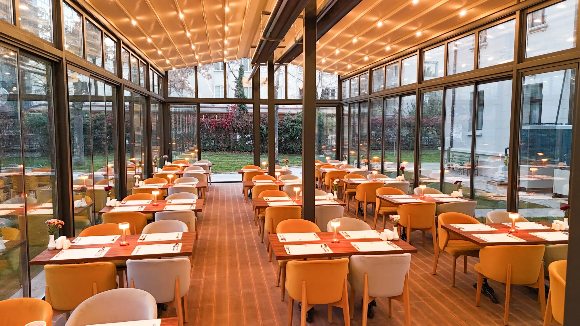 Large glass-walled dining hall with rows of tables and orange chairs