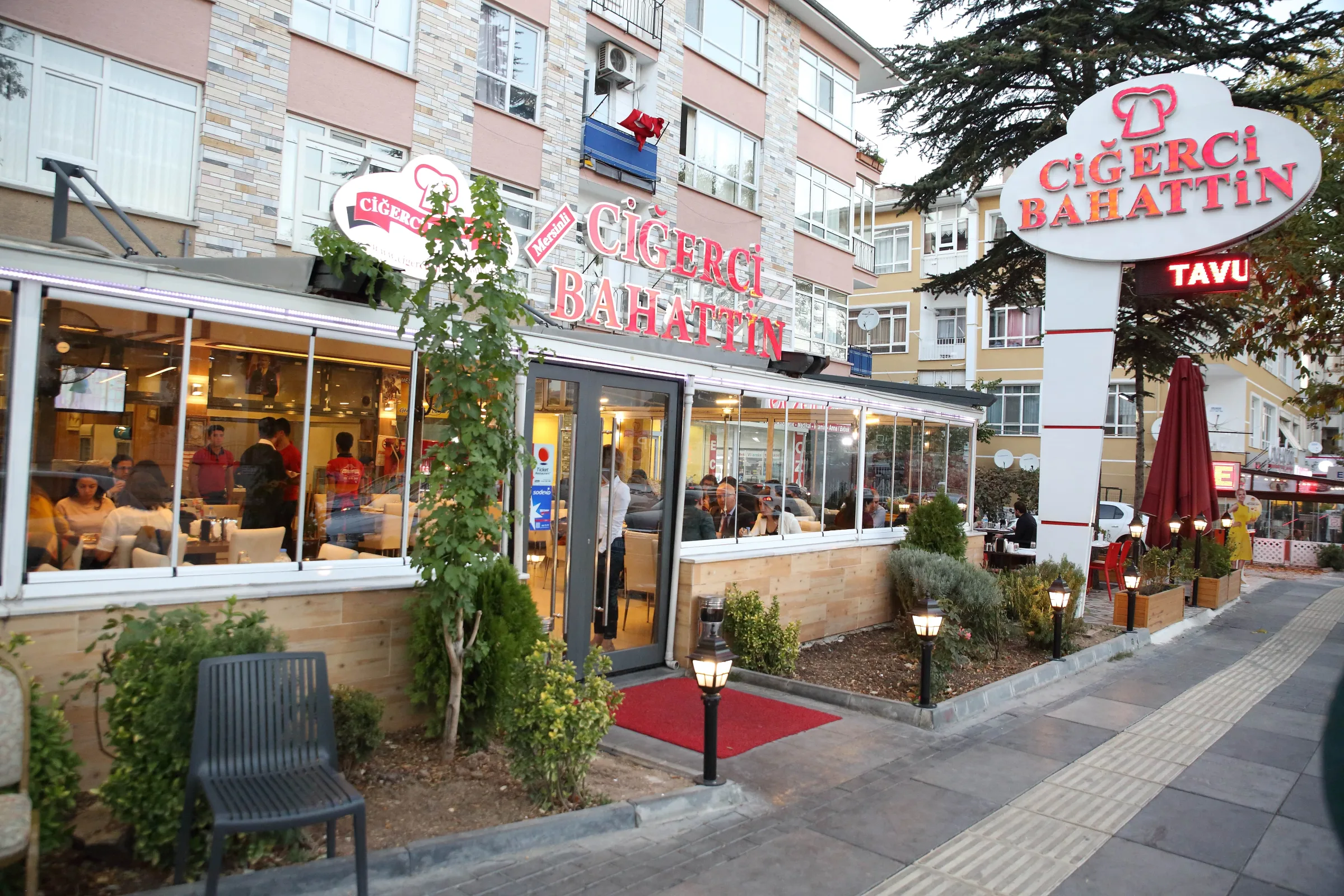 Front of Ciğerci Bahattin with its red sign, glass dining room and planted terrace