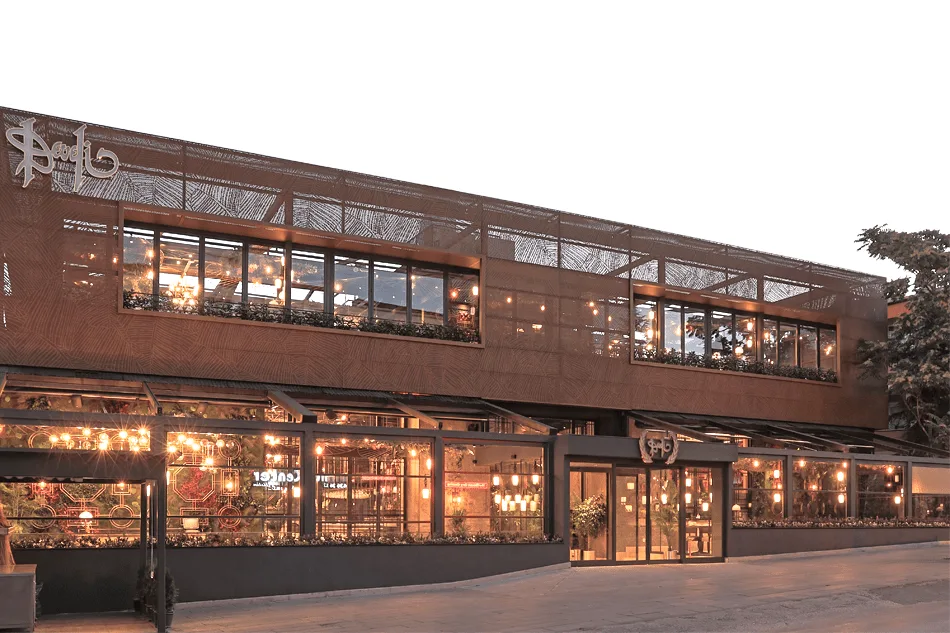 Two-storey Develi Ankara building with a lit glass front at dusk